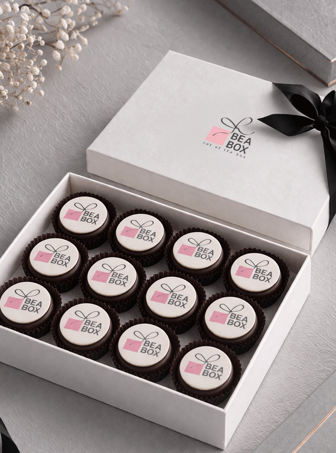 Bijela luksuzna kutija s 12 personaliziranih pralina, ukrašena logotipom i crnom satenskom trakom.