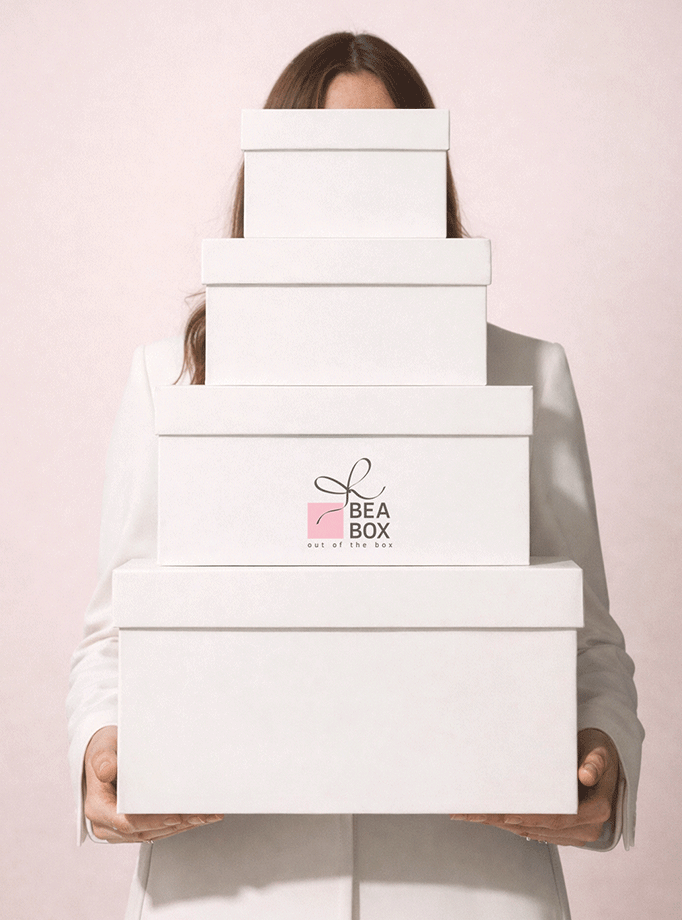 Žena drži set naslaganih luksuznih bijelih poklon kutija različitih veličina.